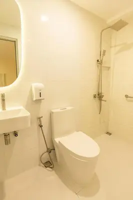 a white bathroom with a toilet and a sink at Hotel Dreamworld East Ortigas in Manila