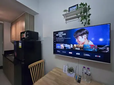 a flat screen tv hanging on a wall with a table at 1BR Condotel with Balcony at FAME Residences #FM30 in Manila