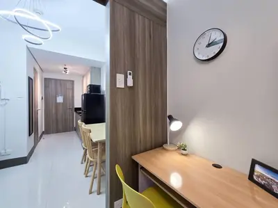 a room with a clock on the wall and a table at 1BR Condotel with Balcony at FAME Residences #FM31 in Manila