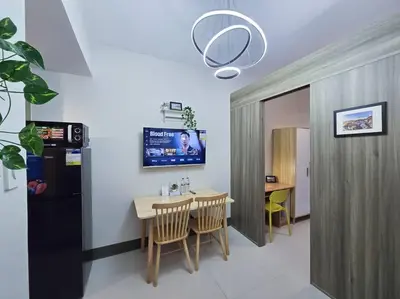 a dining room with a table and a tv on the wall at 1BR Condotel with Balcony at FAME Residences #FM31 in Manila