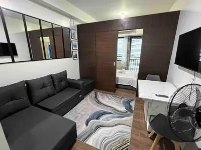 a living room with a black couch and a tv at AIR Residences - 1 Bedroom Unit with Wifi and Netflix in Manila