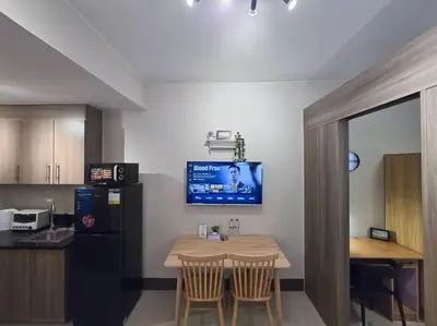 a kitchen with a table and a tv on the wall at 1BR Condotel with Balcony at FAME Residences #FM32 in Manila
