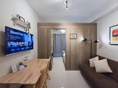 a living room with a wooden table and a couch at 1BR Condotel with Balcony at FAME Residences #FM32 in Manila