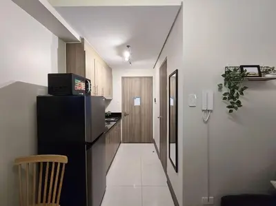 a hallway leading to a kitchen with a black refrigerator at 1BR Condotel with Balcony at FAME Residences #FM38 in Manila