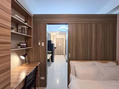 a bedroom with a bed and a desk and a hallway at 1BR Condotel with Balcony at FAME Residences #FM38 in Manila