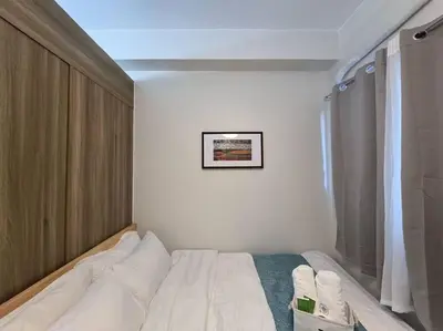 a bedroom with a white bed and a picture on the wall at 1BR Condotel with Balcony at FAME Residences #FM38 in Manila