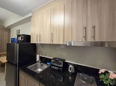 a kitchen with a sink and a black counter top at 1BR Condotel with Balcony at FAME Residences #FM38 in Manila