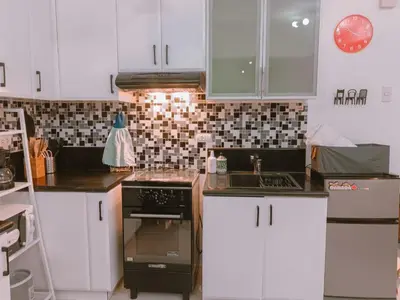 a kitchen with white cabinets and a stove top oven at Bright & Airy Studio near Venice Mall with Pool, Gym & Fast WiFi in Manila