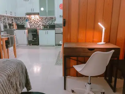 a desk with a white chair and a candle on it at Bright & Airy Studio near Venice Mall with Pool, Gym & Fast WiFi in Manila