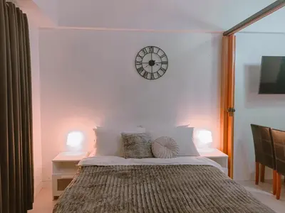 a bedroom with a bed with a clock on the wall at Bright & Airy Studio near Venice Mall with Pool, Gym & Fast WiFi in Manila