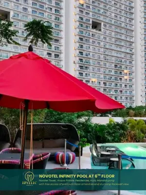 a red umbrella sitting next to a pool with buildings at Novotel Tower at Mandaluyong Rockwell View in Manila