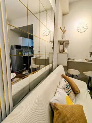 a living room with a white couch and a mirror at Sun and Moon cozywhite Air Residences Makati in Manila