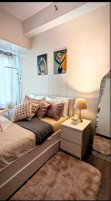 a bedroom with a bed and a table with a lamp at Sun and Moon cozywhite Air Residences Makati in Manila