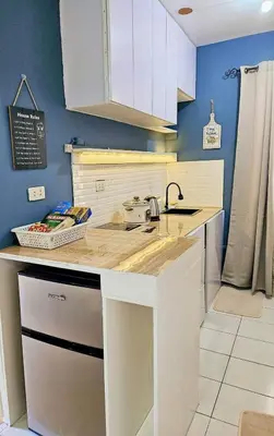 a kitchen with white cabinets and a counter top at Bubu and son suites staycation beside enchanted kingdom in Santa Rosa