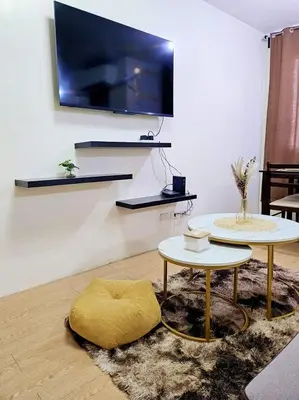 a living room with a yellow ottoman and a tv at Bubu and son suites staycation beside enchanted kingdom in Santa Rosa