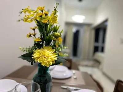 a green vase filled with yellow flowers on a table at Relax and Unwind at Uptown BGC in Manila