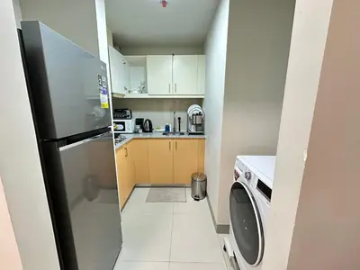 a small kitchen with a refrigerator and a washing machine at Relax and Unwind at Uptown BGC in Manila