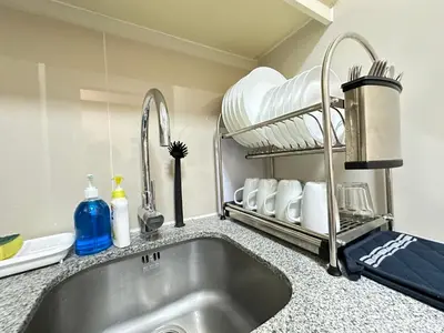 a kitchen counter with a sink and a shelf with dishes at Relax and Unwind at Uptown BGC in Manila