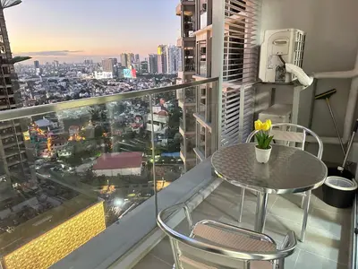a table and chairs on a balcony with a view of a city at Relax and Unwind at Uptown BGC in Manila