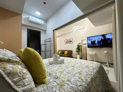 a bedroom with a bed with a tv on the wall at Relax and Unwind at Uptown BGC in Manila