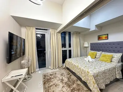 a bedroom with a large bed and a tv at Relax and Unwind at Uptown BGC in Manila