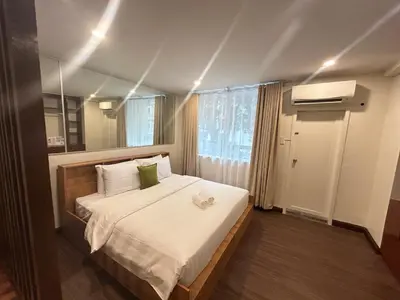 a bedroom with a bed with white sheets and a mirror at Makati Medical City Accommodation in Manila