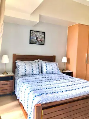 a bed in a bedroom with two lamps and a picture on the wall at Uptown Parksuites BGC with Balcony in Manila