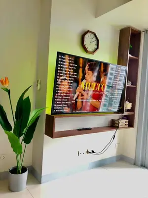 a flat screen tv on a wall with a clock at Uptown Parksuites BGC with Balcony in Manila
