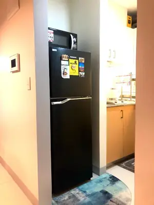 a black refrigerator with stickers on it in a kitchen at Uptown Parksuites BGC with Balcony in Manila