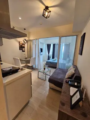 a room with a bed and a kitchen and a living room at Azure Urban Resort Residences in Manila