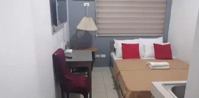 a small bedroom with a bed and a desk with a red chair at Urban Deca Tower OYO 2 in Manila