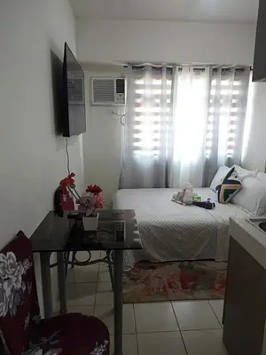 a bedroom with a bed and a table and a window at Urban Deca Tower OYO 2 in Manila