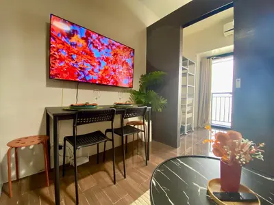 a living room with a table and a tv on the wall at Air Residence-Sunset & City Views Await in Manila