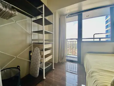 a bedroom with a bed and a book shelf next to a window at Air Residence-Sunset & City Views Await in Manila