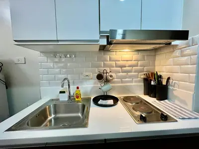 a kitchen counter with a sink and a stove at Air Residence-Sunset & City Views Await in Manila