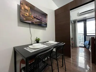 a dining room with a black table and chairs at Air Residence-Sunset & City Views Await in Manila
