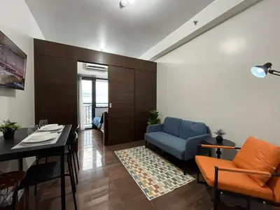 a living room with a blue couch and a table at Air Residence-Sunset & City Views Await in Manila