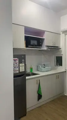 a kitchen with white cabinets and a black refrigerator at Staycation One bedroom in Manila