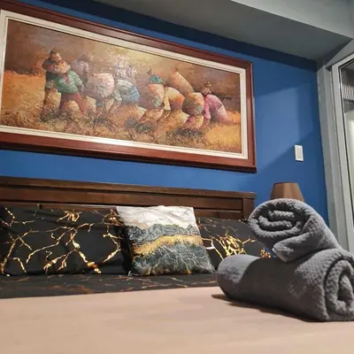 a painting on a blue wall above a bed at Azure Paranaque near Airport in Manila
