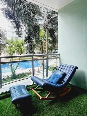 a blue reclining chair in a room with a large window at Azure Paranaque near Airport in Manila