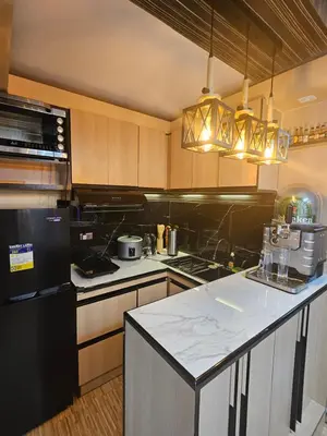 a kitchen with a black refrigerator and a white counter top at Dlighful Pad's MassageChair FreeParking Bar Park Garden in Manila
