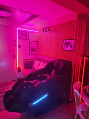 a woman laying on a couch in a room with pink lights at Dlighful Pad's MassageChair FreeParking Bar Park Garden in Manila
