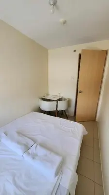 a bedroom with a white bed and a table at URBAN DECA R1125 Ortigas SM EAST in Manila