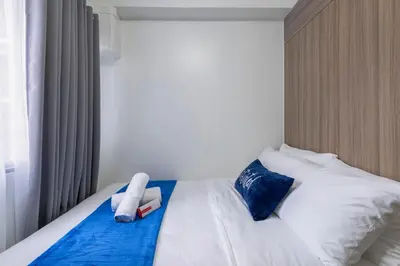 a bedroom with a bed with white sheets and blue pillows at Oasis Urban Stay 2 in Manila