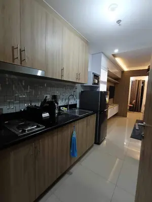a kitchen with wooden cabinets and a black counter top at The SK home at the shore in Manila