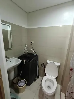 a bathroom with a white toilet and a sink at The SK home at the shore in Manila