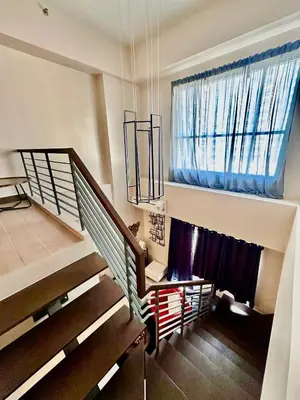 a living room with a staircase and a window at Cozy Loft in Makati in Manila