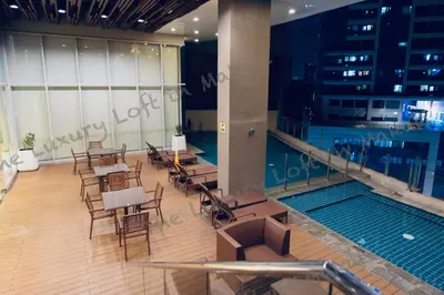 a room with tables and chairs and a swimming pool at Cozy Loft in Makati in Manila