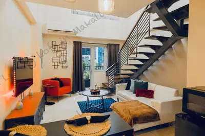 a living room with a staircase and a couch and a table at Cozy Loft in Makati in Manila