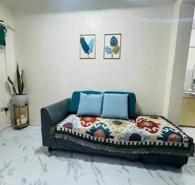 a living room with a couch with a colorful blanket at MiKasa Azul Transient House in Cabuyao